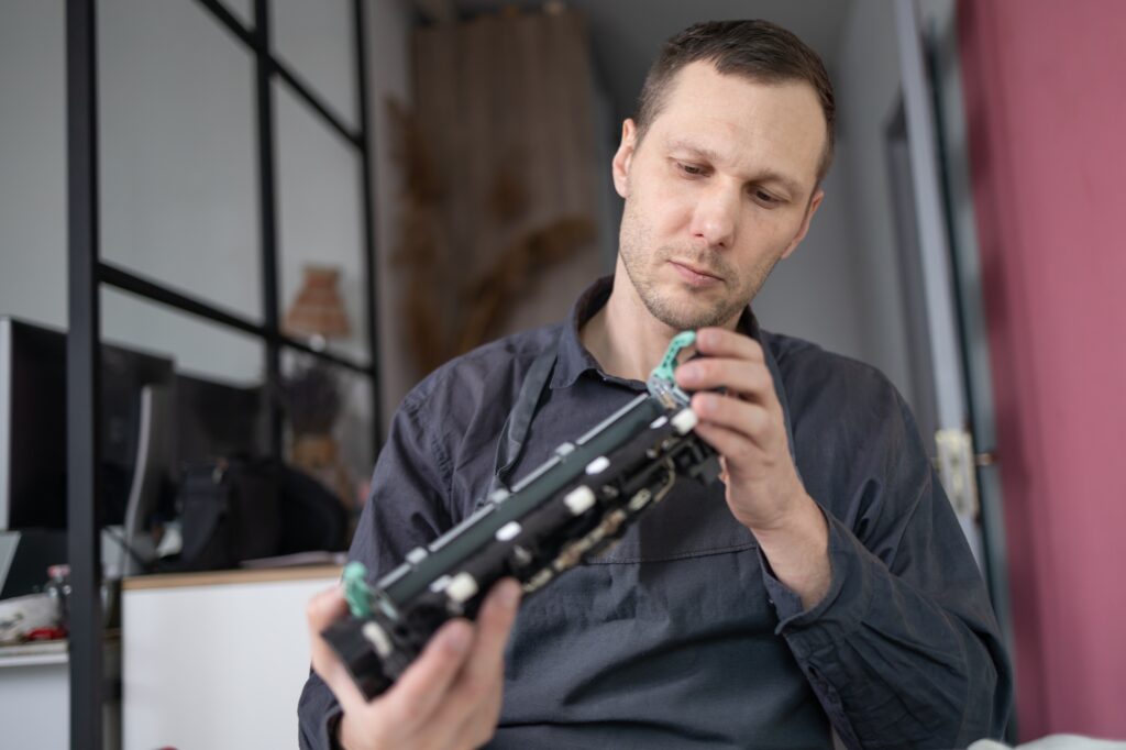 Specialist repairs the printer cartridge, fuser unit close-up. printer repair technician.
